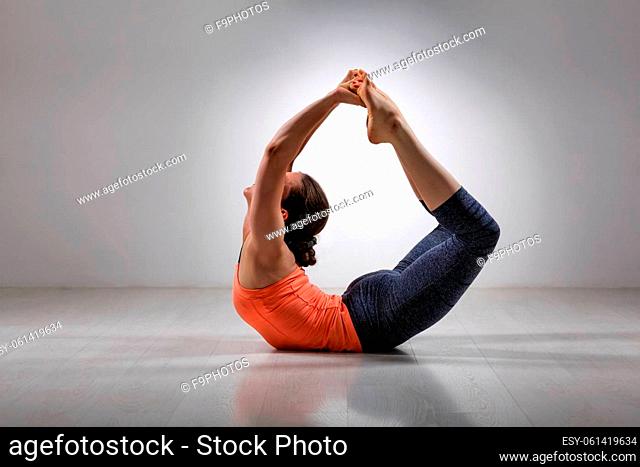 Sporty fit woman practices yoga asana Dhanurasana - bow pose