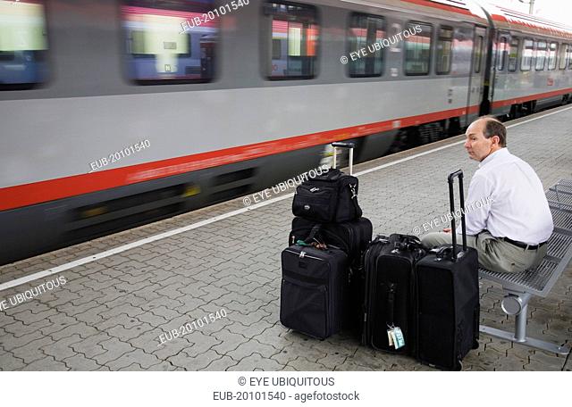 Wien Westbahnhof. Passenger with luggage sitting on Vienna West Station with passing train. Also known as Vienna Western Station this is a major Austrian...