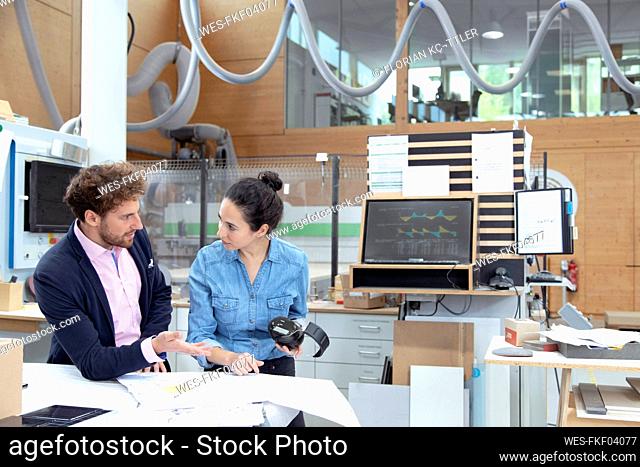 Male and female entrepreneurs discussing over strategy in factory