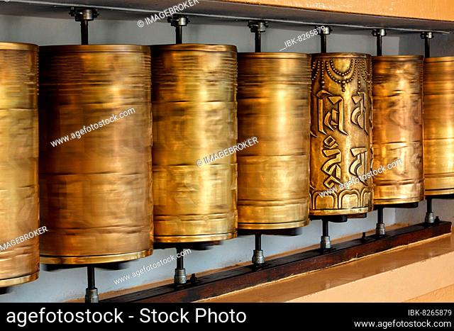 Rotating motion blurred metal buddhist prayer wheels with Om Mani Padme Hum mantra meaning Praise to Jewel in Lotus in Tsuglagkhang complex in Dalai Lama...