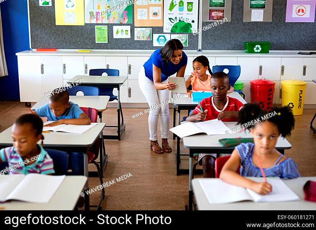 African american female teacher with digital tablet teaching a girl at elementary school