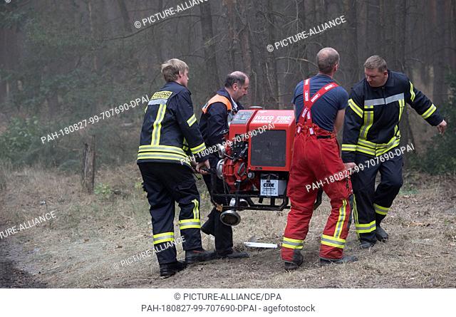 27 August 2018, Treuenbrietzen, Germany: Firefighters tow a water pump in a forest near Treuenbrietzen. About 350 firefighters are still on duty to fight forest...