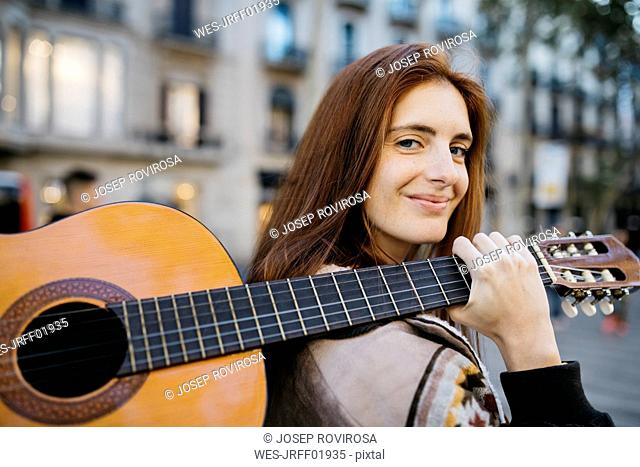 Red-haired woman with a guitar in the city