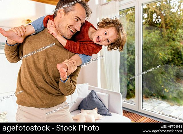 Happy father carrying daughter on shoulders at home