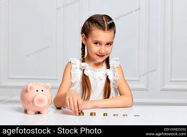 cute little child girl counts coins. kid with piggy bank at home