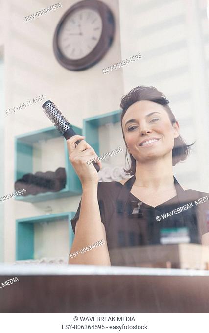 Smiling hairdresser holding hair brush