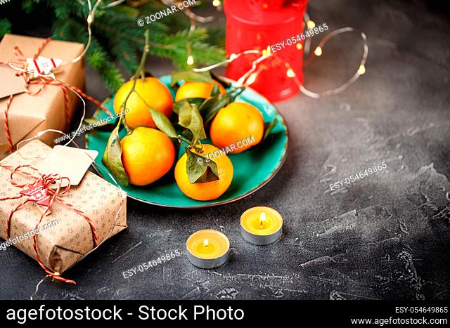 Tangerines in green plate with candles and gift boxes