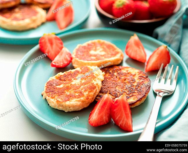Sweet cheese pancakes on plate served strawberries. Cottage cheese pancakes, syrniki, ricotta fritters, curd fritters, Copy space for text or design