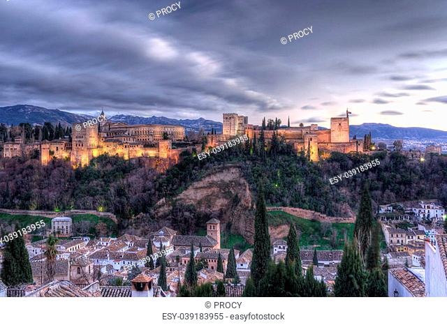 the alhambra palace at twilight, in granada (spain), with sierra nevada mountains in the background