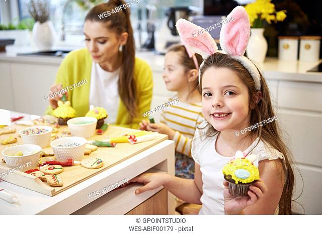 Portrait of smiling girl showing Easter cupcake in kitchen