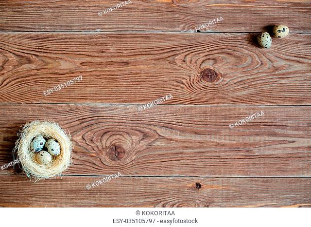 Brown wooden backgrond with nest with quail eggs in a corner
