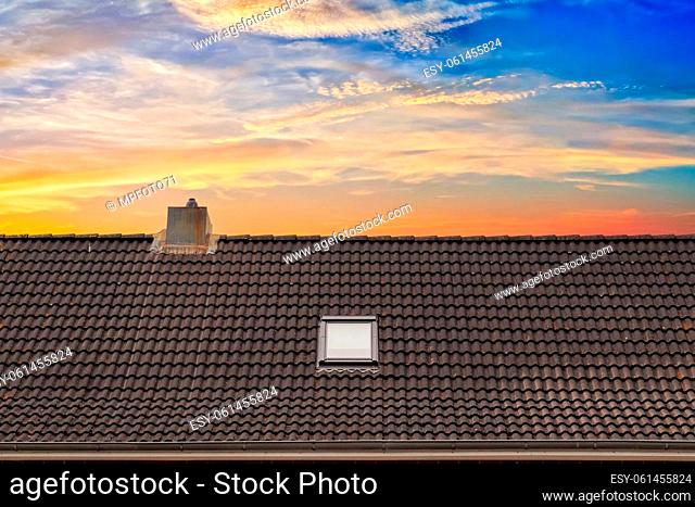 Roof window in velux style with dark roof tiles