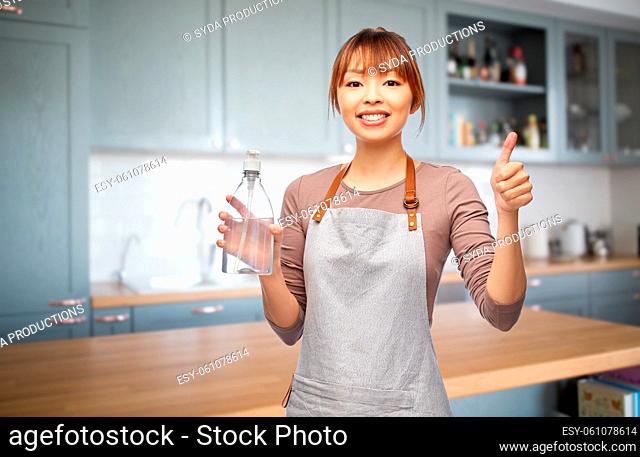 happy woman in apron with hand sanitizer or soap