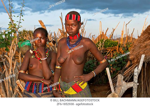 Turmi Ethiopia Africa village Lower Omo Valley Hamar Hammer tribe two nude teemager girls at sunset in village fence 23