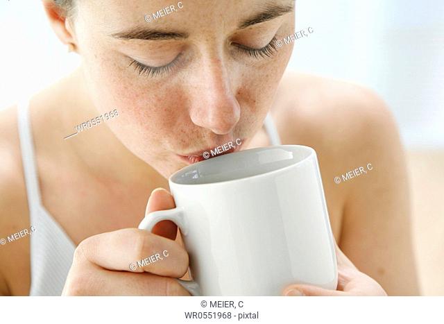 portrait - young woman is drinking tea out of a tea cup