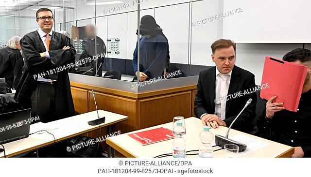 04 December 2018, Lower Saxony, Celle: A witness for the prosecution covers his face in a courtroom of the Higher Regional Court next to his defender Burkhard...