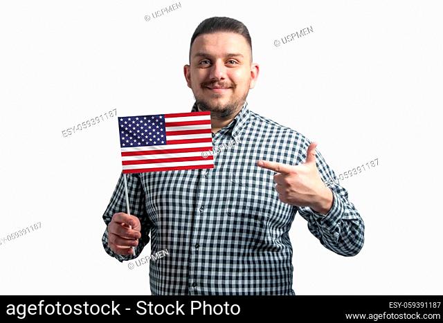 White guy holding a flag of United States and points the finger of the other hand at the flag isolated on a white background