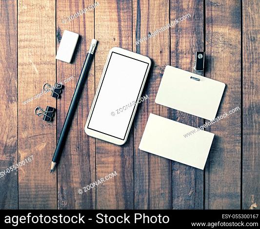 Smartphone and blank stationery on vintage wooden background. Responsive design template. Flat lay
