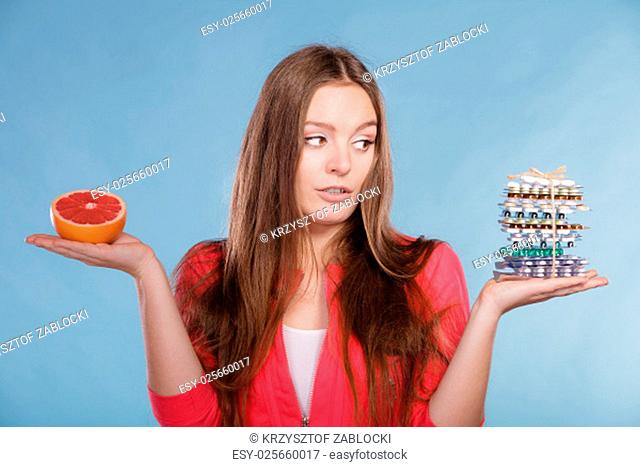 woman girl holding diet weight loss tablets pills and grapefruit. choice between natural and synthetic way of slimming dieting. health care