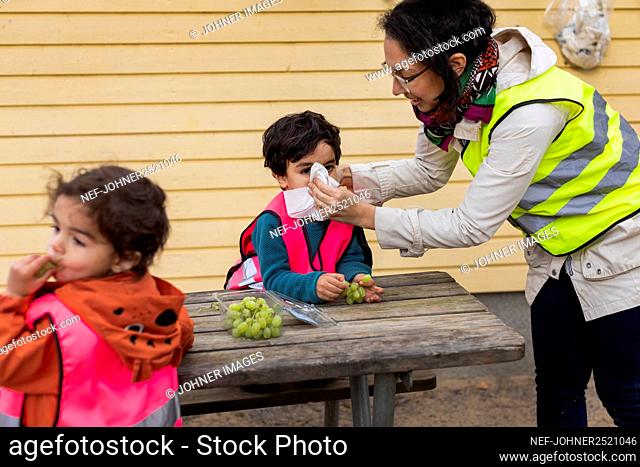 Preschool teacher and students eating grapes outdoors