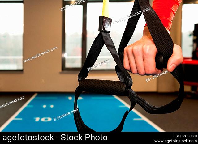 Male hands hold fitness straps in gym