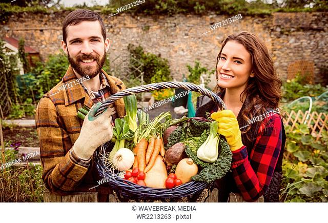 Smiling couple holding basket of vegetable