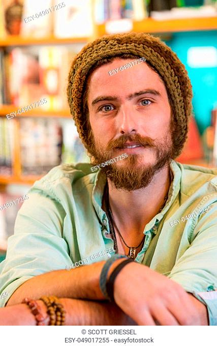 Handsome young man with knit cap in book store or library