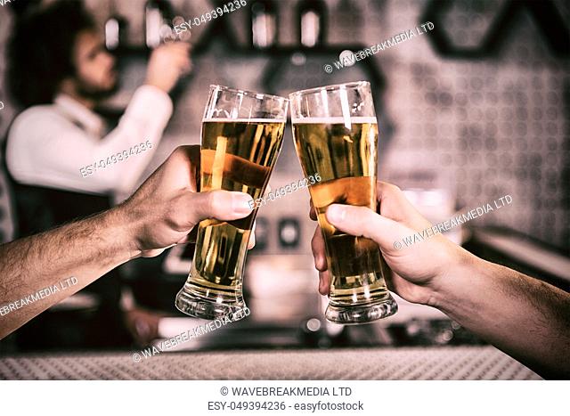 Cropped image of men toasting beer glass at bar