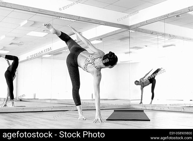 Fit sporty active girl in fashion sportswear doing yoga fitness exercise in in yoga studio. Active urban lifestyle. Black and white photo