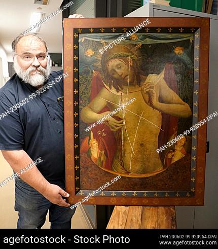 02 June 2023, Hamburg: Sexton Martin Meier stands next to the damaged painting ""Christ as Man of Sorrows"" in a room in the main church of St. Peter