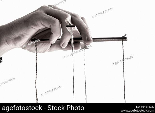 Close-up Of A Person's Hand Manipulating Marionette With String On Gray Background
