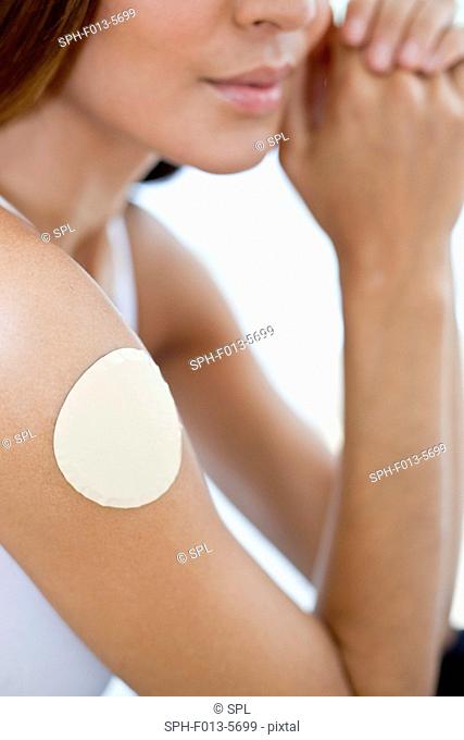 MODEL RELEASED. Young woman wearing a nicotine patch on her arm