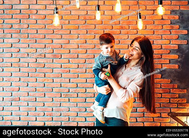 Mother and young son posing on brick wall background