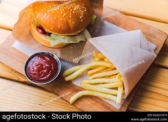 Fresh tasty burger and french fries on wooden table. french fries and bbq sauce on wood plate. street food burger and fried potatoes. Unhealthy food
