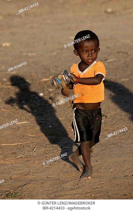 Boy, 3 years old, with a toy made of cans, Morondava, Madagascar