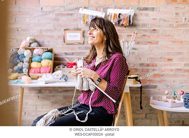 Smiling woman sitting on chair knitting