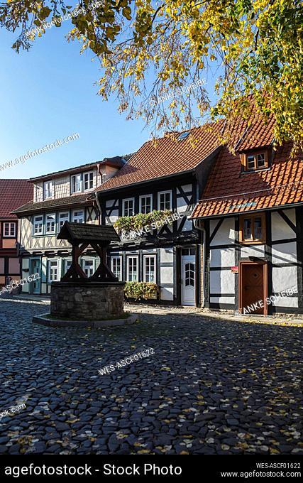 Germany, Saxony-Anhalt, Wernigerode, Half-timbered townhouses along cobblestone street with well in foreground
