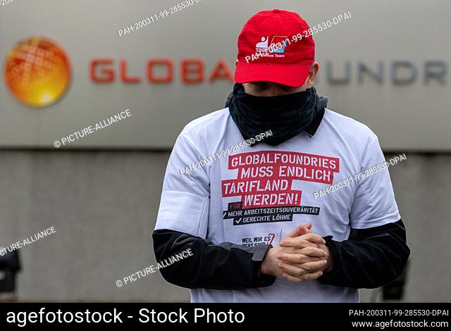 11 March 2020, Saxony, Dresden: A token strike participant stands in front of the Globalfoundries factory gate. The IG Bergbau, Chemie, Energie (Mining