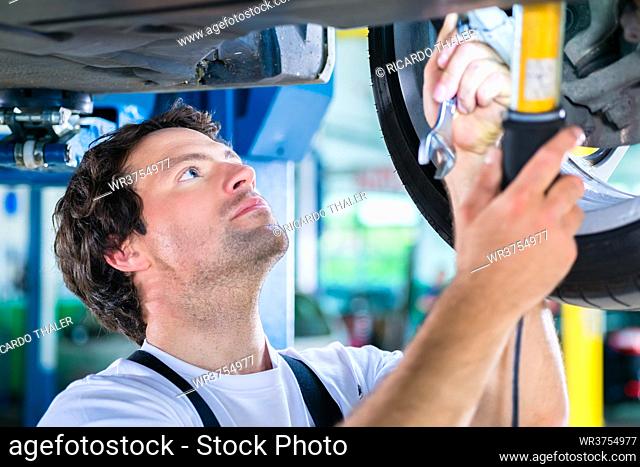 Car mechanic working in car workshop on wheel