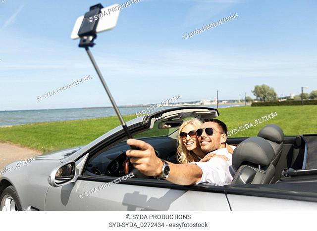 happy couple in car taking selfie by smartphone