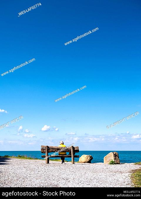 Woman sitting on bench near sea