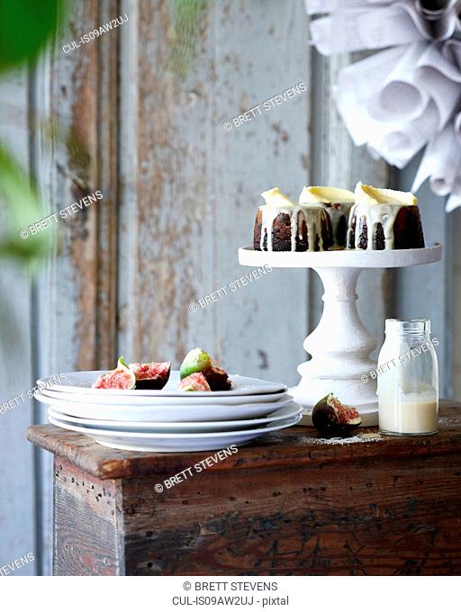 Mini christmas puddings with figs on stack of plates on patio table