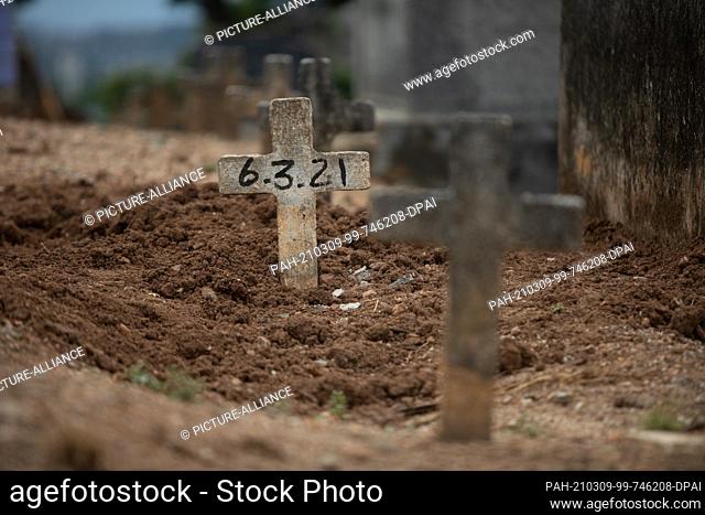 06 March 2021, Brazil, Rio De Janeiro: A simple cross with no name and a date of 6/3/2021 stands at grave at Iraja Cemetery