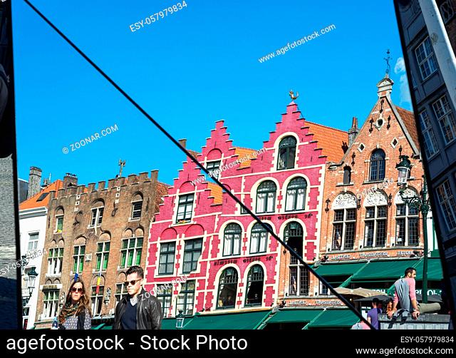Split mirror of historic gabled buildings and cafes in Market Square Bruges West Flanders in Belgium