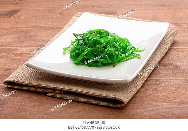 White plate with chuka seaweed and napkin on the wooden table