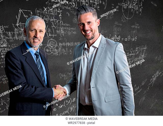 Business men shaking hands against grey wall with math doodles