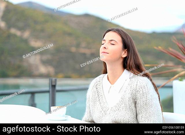 Relaxed girl breathing fresh air with closed eyes in a coffee shop terrace