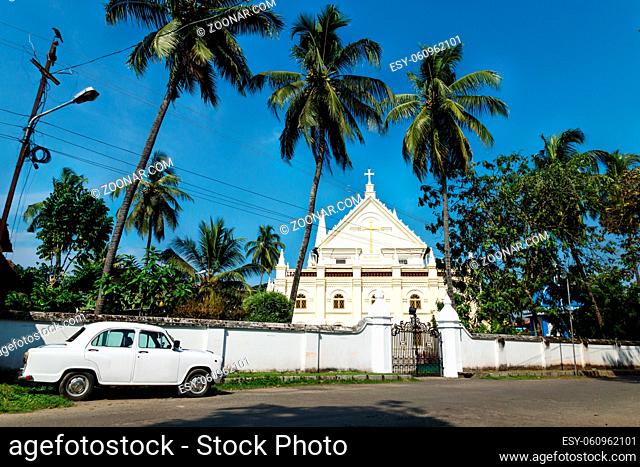 White oldtimer car Santa Cruz Cathedral Basilica white colonial church with blue cloudless sky in Kochi, Kerala, India
