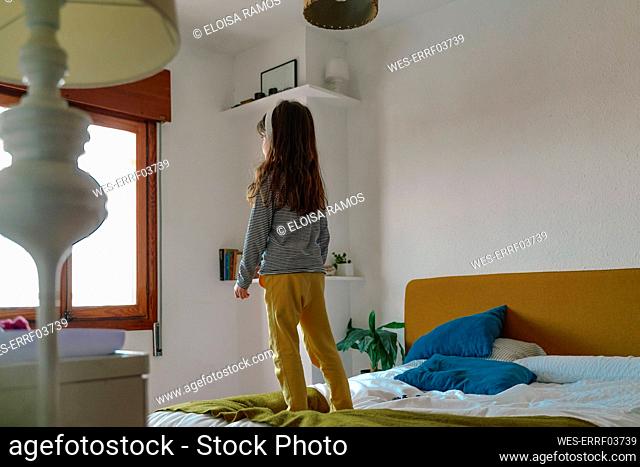 Girl standing on bed and listening music with headphones