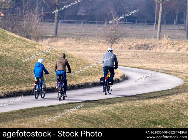 02 March 2021, Lower Saxony, Bleckede: Cyclists are on the path behind the Elbe dike. The Elbe cycle path is much used by cycle tourists